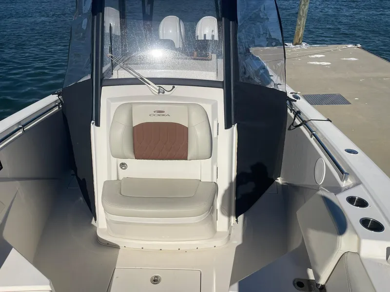 Slide: The Image of 2023 Cobia 320 CC boat interior with seating and windshield at dock. - 19