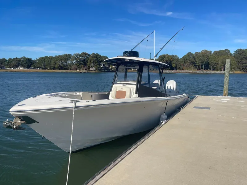 Slide: The Image of 2023 Cobia 320 CC boat docked on a sunny day. - 2