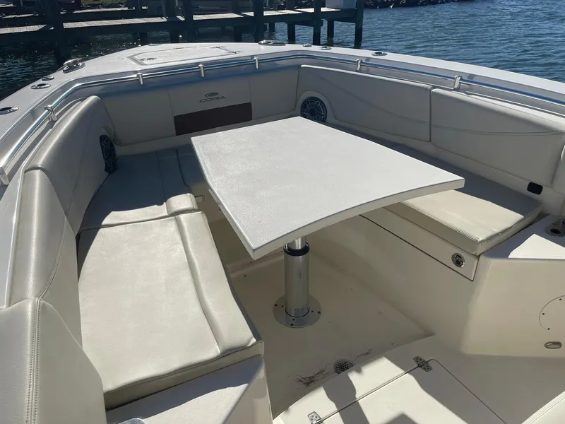 Slide: The Image of 2023 Cobia 320 CC boat interior with seating and table, dockside view. - 24