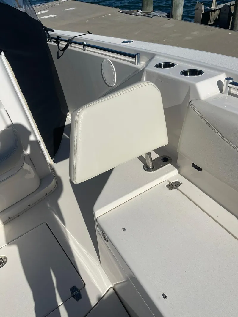 Slide: The Image of 2023 Cobia 320 CC boat interior with white seating and cup holders. - 26