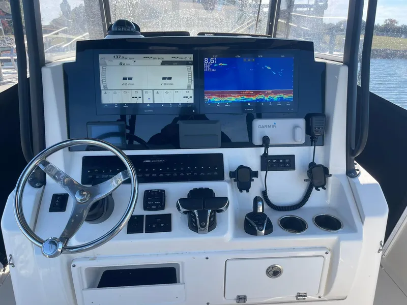 Slide: The Image of Cobia 320 CC 2023 helm with Garmin displays and controls on a sunny day. - 27