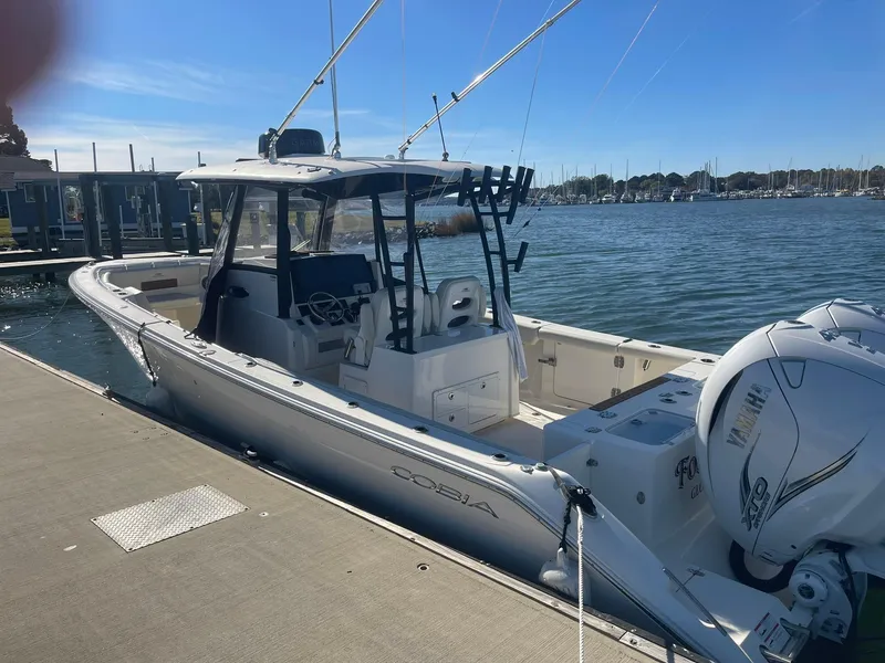 Slide: The Image of 2023 Cobia 320 CC boat docked by the water on a sunny day. - 3