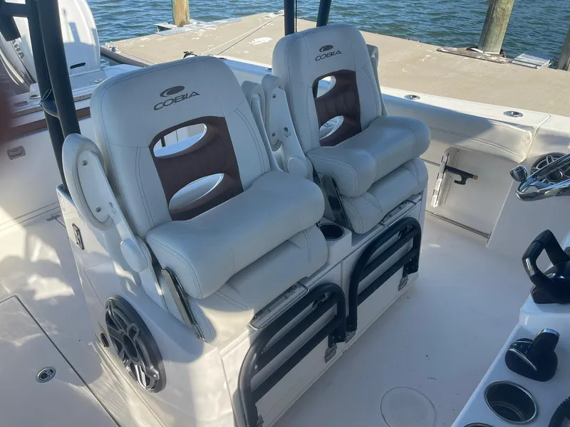 Slide: The Image of 2023 Cobia 320 CC boat interior with dual cushioned seats by the water. - 9
