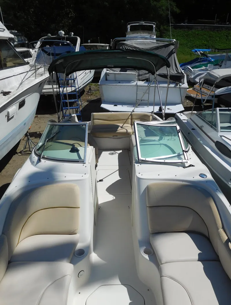Slide: The Image of 2002 Sea Ray 240 Sundeck boat with open seating and canopy, docked among other boats. - 12