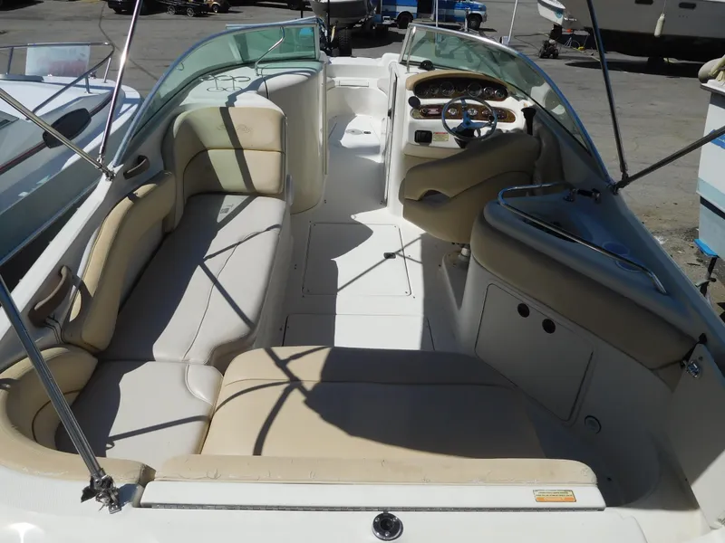 Slide: The Image of 2002 Sea Ray 240 Sundeck boat interior with beige seating and steering console. - 4