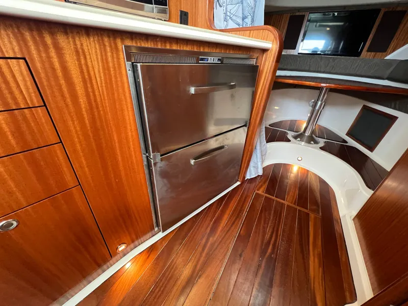 Slide: The Image of 2016 Pursuit OS 385 Offshore interior with wood flooring and stainless steel fridge. - 47