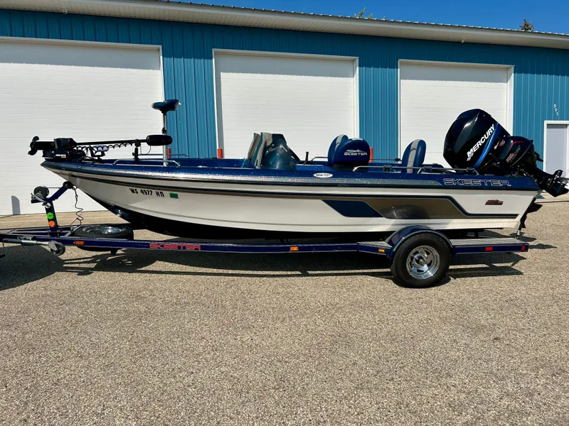 Slide: The Image of 2005 Skeeter WX 1880 boat on trailer, parked outside blue building. - 28