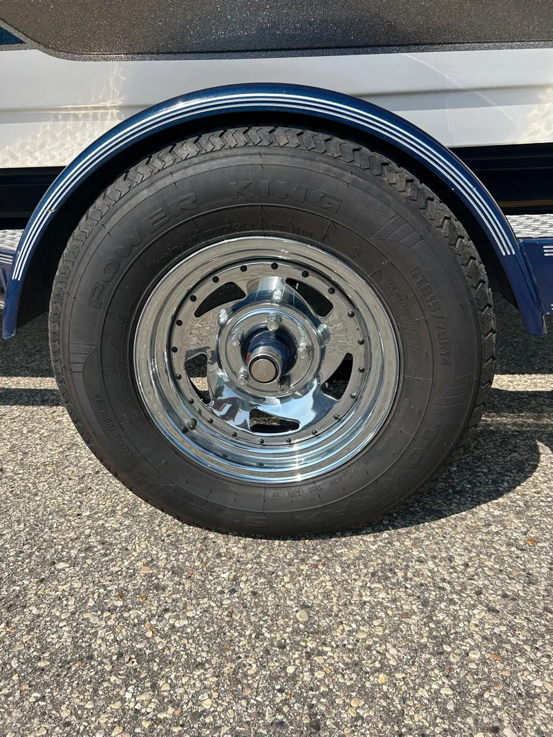 Slide: The Image of 2005 Skeeter WX 1880 trailer wheel with chrome rim on asphalt. - 41