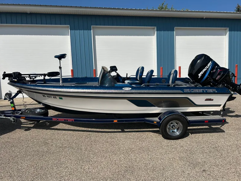 Slide: The Image of 2005 Skeeter WX 1880 fishing boat on trailer, parked in front of blue garage. - 43