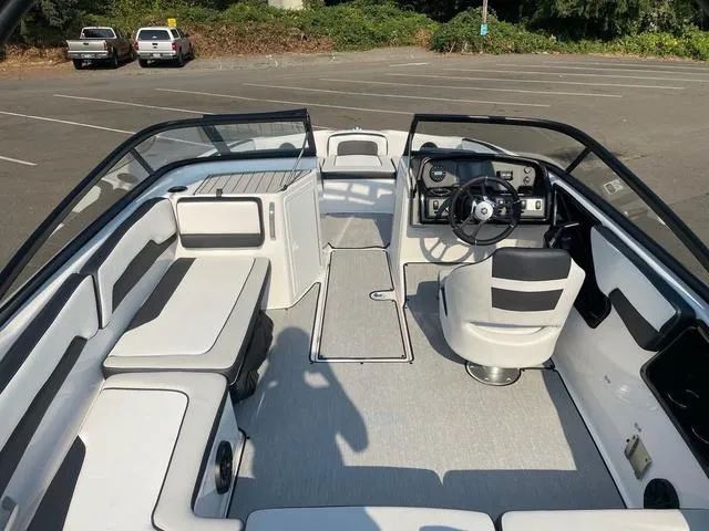 Slide: The Image of 2025 Yamaha Boats AR195 interior with sleek seating and modern dashboard in a parking lot. - 8