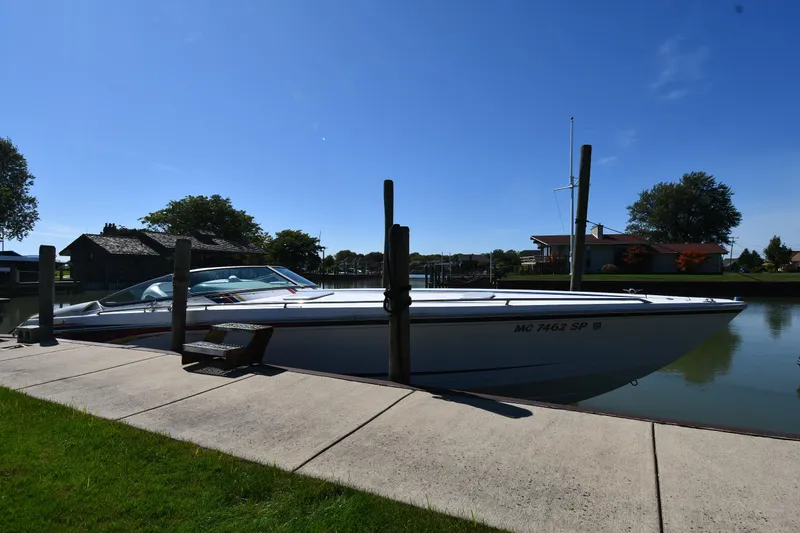 Slide: The Image of 2003 Formula 353 FASTech boat docked by a serene waterfront on a sunny day. - 0