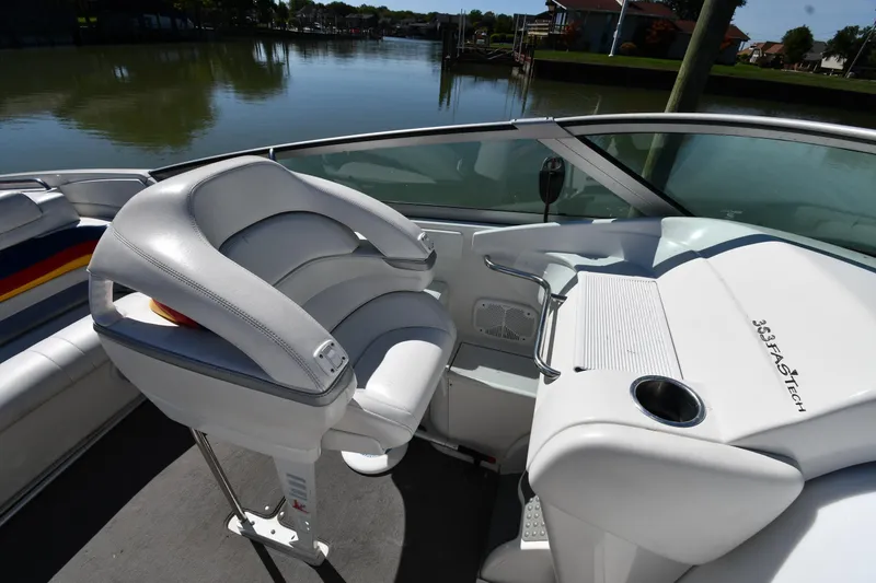 Slide: The Image of 2003 Formula 353 FASTech boat interior with white seating and steering area, near a calm waterway. - 17