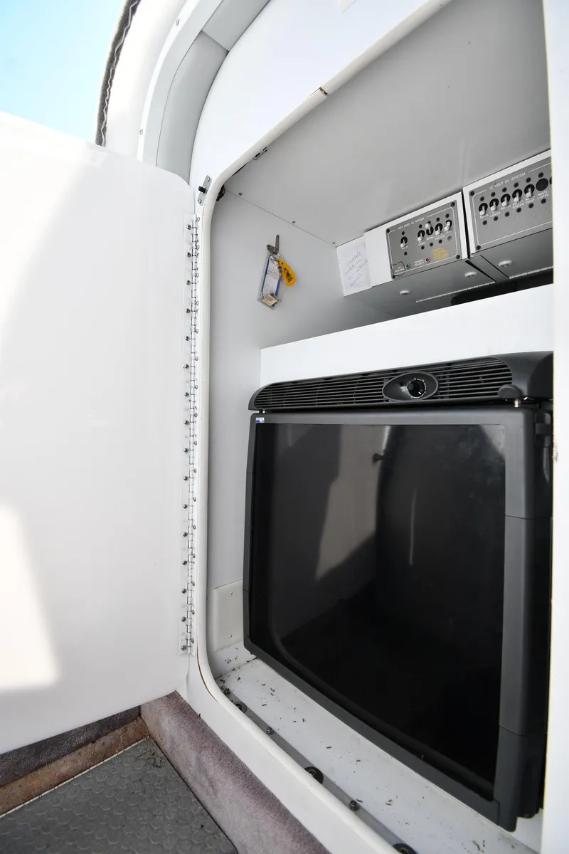 Slide: The Image of 2003 Formula 353 FASTech boat interior storage compartment with control panels and mini fridge. - 41
