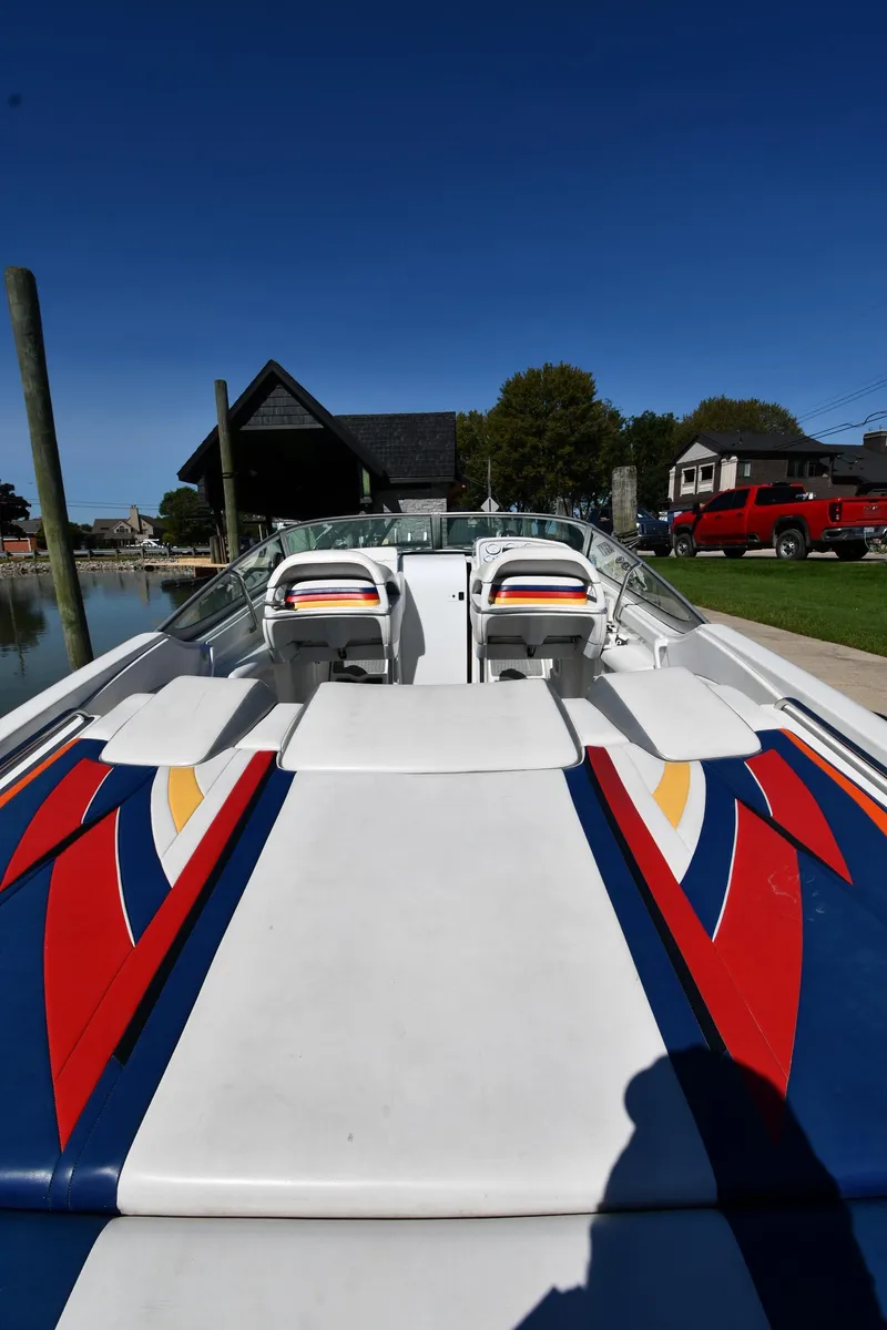 Slide: The Image of 2003 Formula 353 FASTech boat with vibrant graphics, docked near waterfront homes. - 7