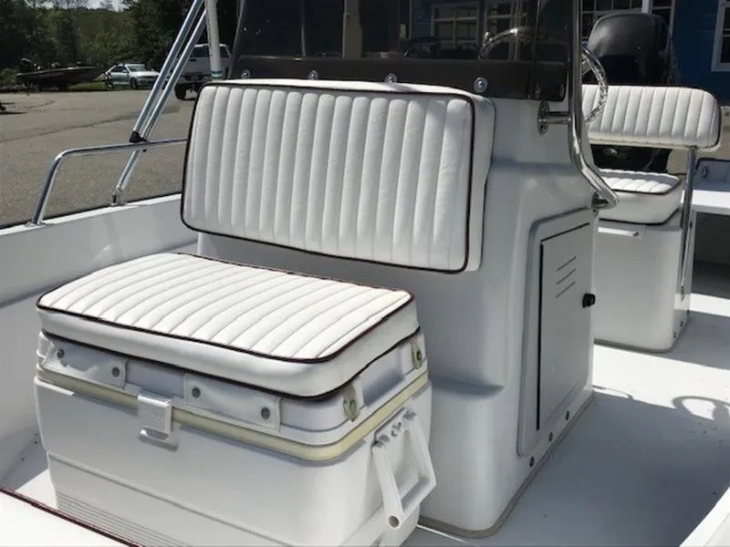 Slide: The Image of 1995 Boston Whaler 150 Dauntless boat interior with cushioned seating and console. - 8