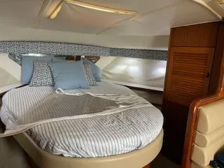 Slide: The Image of 2000 Pursuit 3400 Express cabin with cozy bed and wooden storage. - 14