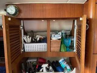 Slide: The Image of Wooden cabinet with open doors, showing organized storage inside a 2000 Pursuit 3400 Express boat. - 16