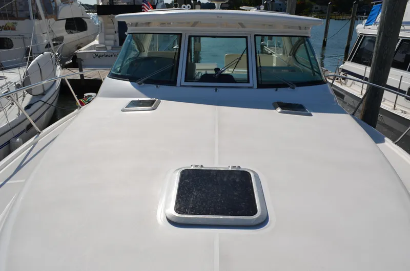 Slide: The Image of 2004 Tiara Yachts 3800 Open docked, showcasing spacious deck and cabin windows. - 14