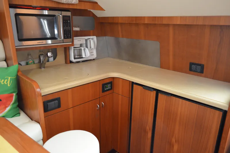 Slide: The Image of 2004 Tiara Yachts 3800 Open kitchen with microwave, coffee maker, and wooden cabinetry. - 46