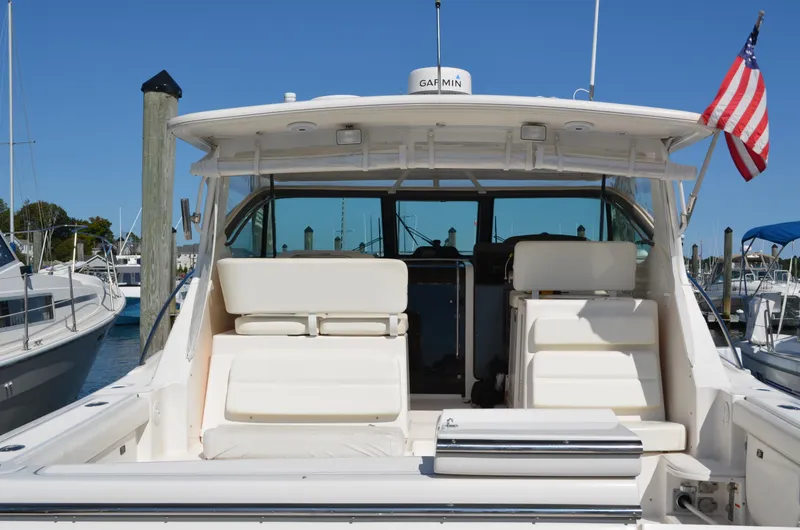 Slide: The Image of 2004 Tiara Yachts 3800 Open at marina, rear view with seating and American flag. - 6