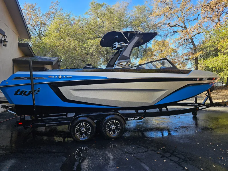 Slide: The Image of 2020 Tigé 25ZX boat on trailer, blue and white, parked outdoors. - 24