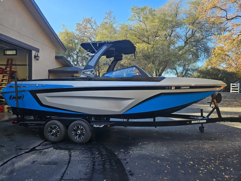 Slide: The Image of 2020 Tigé 25ZX boat in driveway, blue and gray design, on trailer. - 25