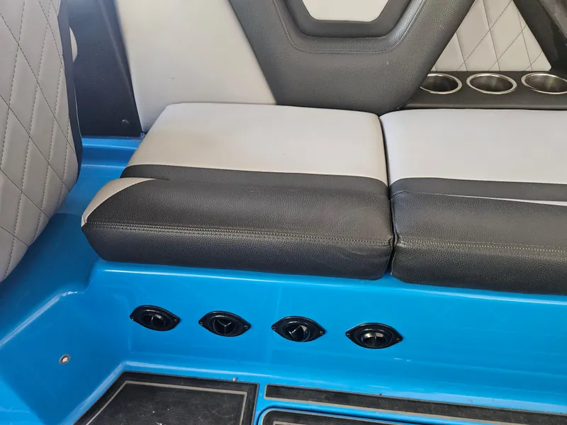 Slide: The Image of 2020 Tigé 25ZX boat interior with black and white seating, blue accents, and cup holders. - 37
