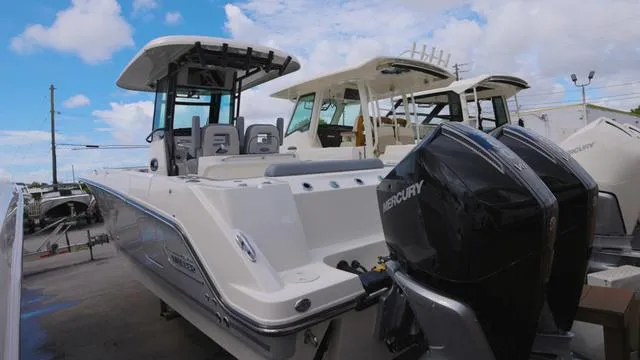 Slide: The Image of 2025 Boston Whaler 280 Outrage boat with dual Mercury engines, docked under a blue sky. - 4