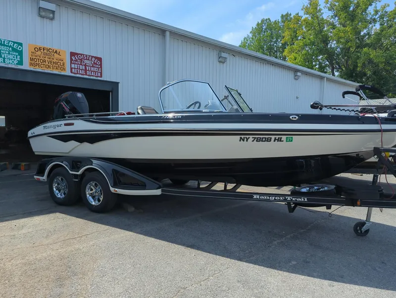 Slide: The Image of 2023 Ranger 2080MS boat on trailer outside a building, sunny day. - 2