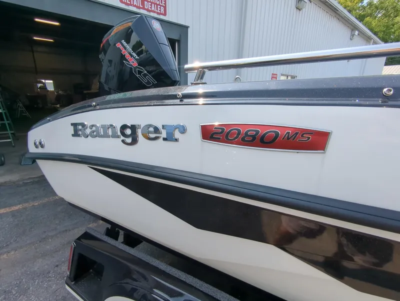 Slide: The Image of 2023 Ranger 2080MS boat, side view with logo, parked near a building. - 4
