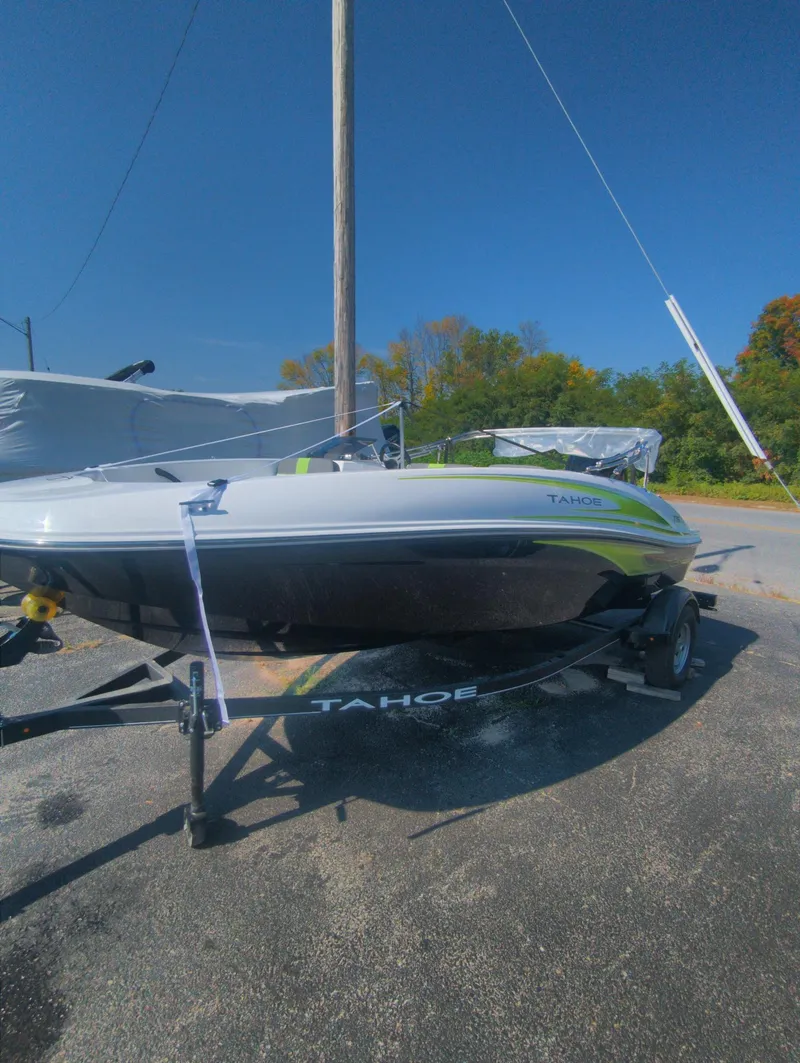 Slide: The Image of 2024 Tahoe T16 boat on trailer, parked outdoors under clear blue sky. - 6