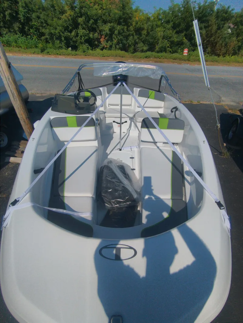 Slide: The Image of 2024 Tahoe T16 boat with seating, parked outdoors, surrounded by greenery. - 7