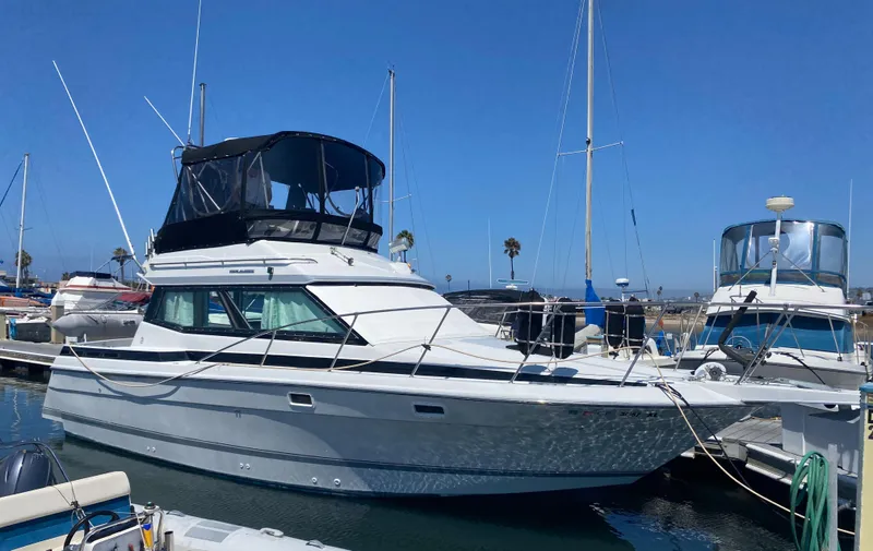 Slide: The Image of 1988 Chris-Craft 320 Amerosport Sedan docked in a marina under clear blue skies. - 0