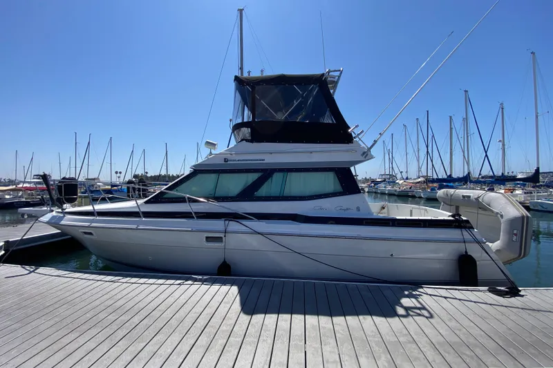 Slide: The Image of 1988 Chris-Craft 320 Amerosport Sedan docked at marina, clear sky background. - 2