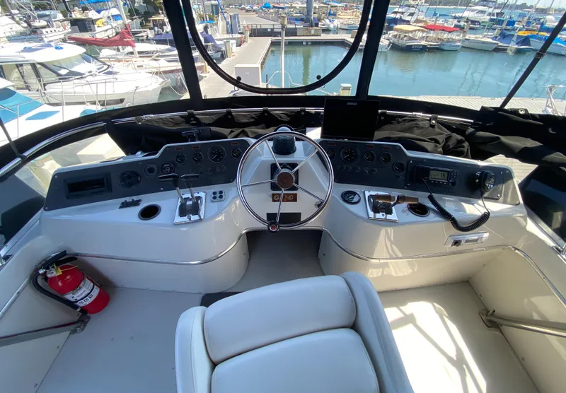 Slide: The Image of 1988 Chris-Craft 320 Amerosport Sedan helm with marina view, featuring steering wheel and controls. - 31