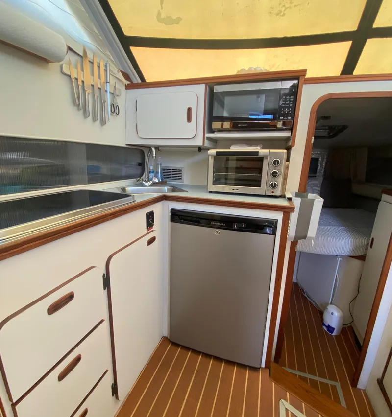 Slide: The Image of 1988 Chris-Craft 320 Amerosport Sedan kitchen with appliances and wood flooring. - 47