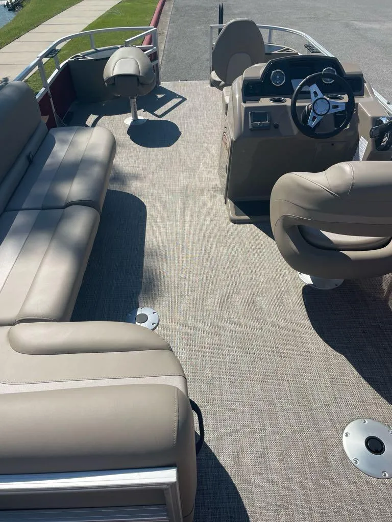 Slide: The Image of 2024 Ranger Reata 200F pontoon boat interior with beige seating and steering console. - 4