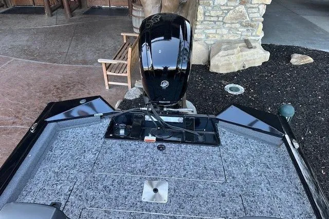 Slide: The Image of 2025 Tracker Pro Team 175 boat with motor, outdoor setting, stone and wood background. - 7