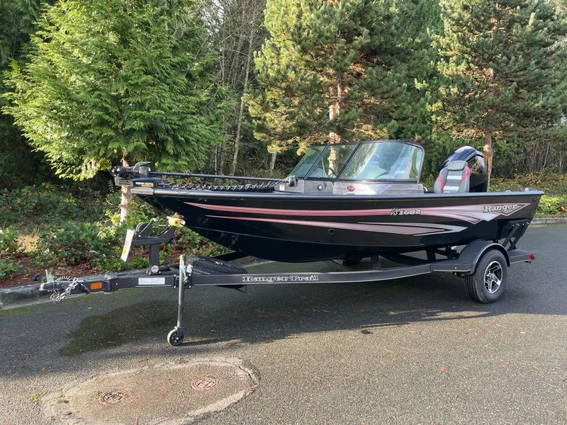 The Image of 2024 Ranger VS1682SC Angler boat on trailer, parked on road near trees. - 0