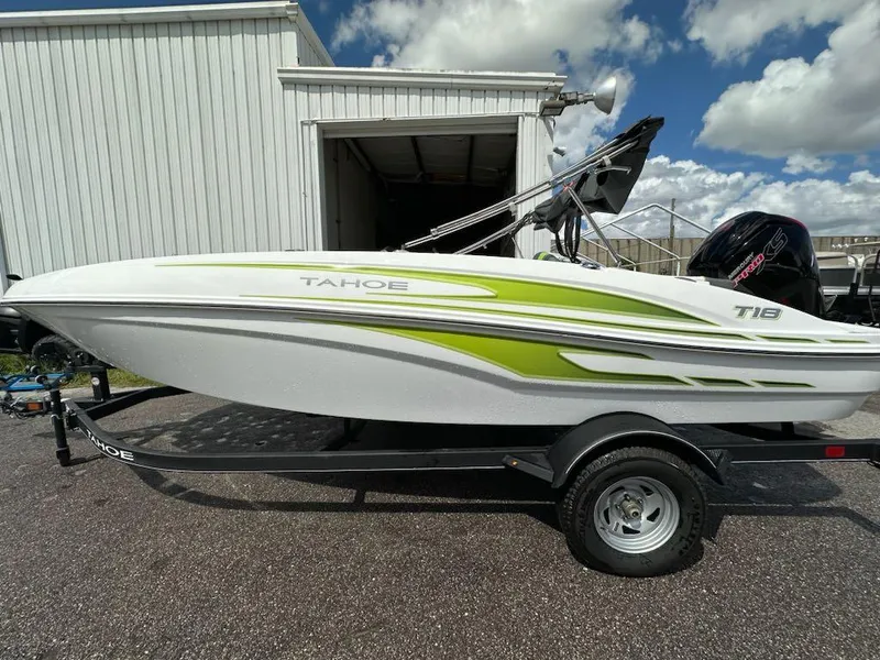 Slide: The Image of 2024 Tahoe T18 boat with green accents on trailer, parked outside a building. - 0