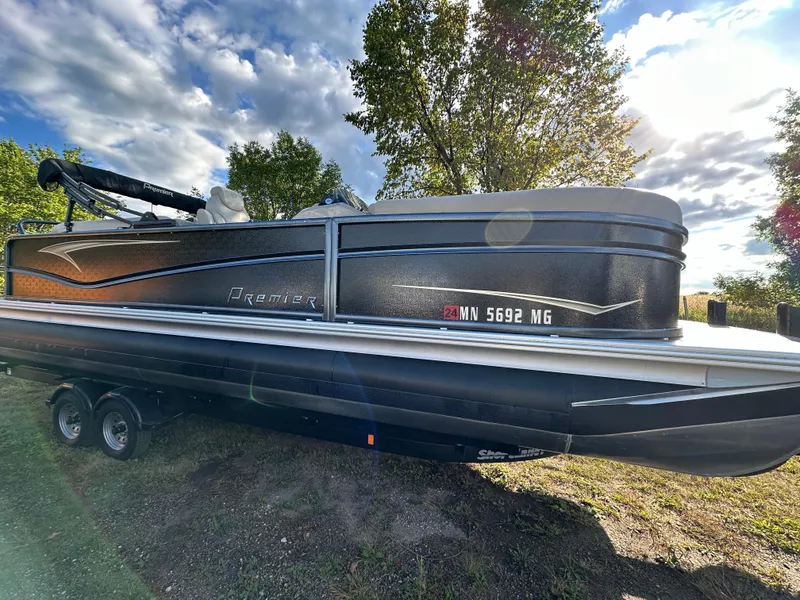 The Image of 2022 Premier 230 SunSation RF pontoon boat on trailer, parked outdoors under a sunny sky. - 0