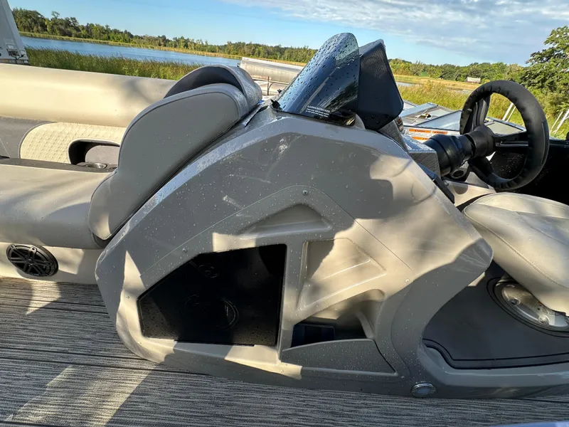 Slide: The Image of 2022 Premier 230 SunSation RF boat interior with steering wheel and seating, near a scenic lake. - 9