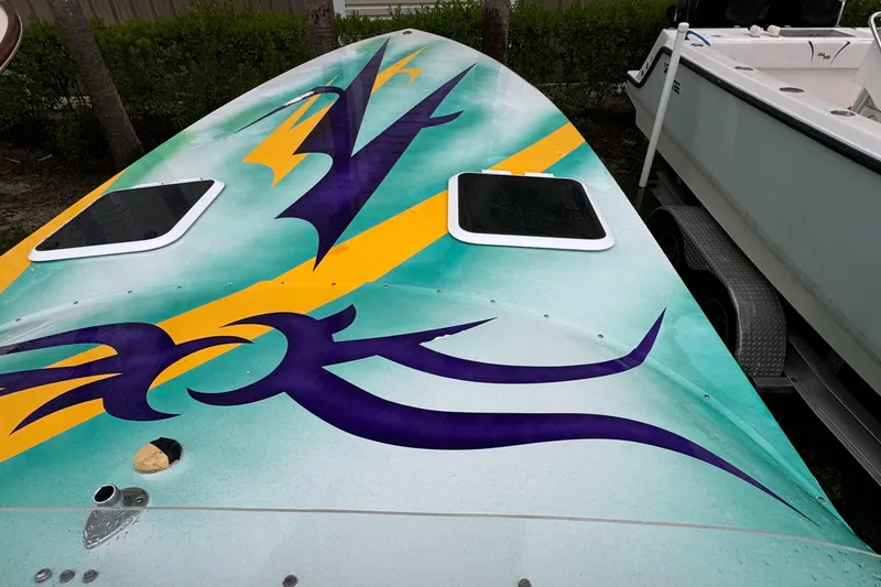 Slide: The Image of 1997 Hustler 32 boat with vibrant purple and yellow graphics on deck. - 10