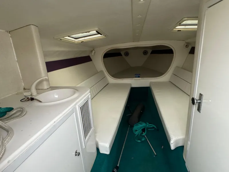 Slide: The Image of Interior of a 1997 Hustler 32 boat with white seating and compact sink. - 7