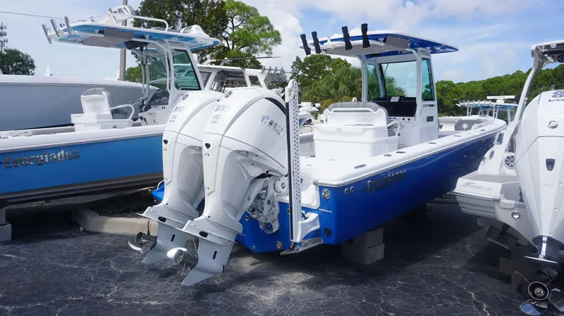 Slide: The Image of 2025 Everglades 273 CC boat with dual engines, blue and white design, parked outdoors. - 2