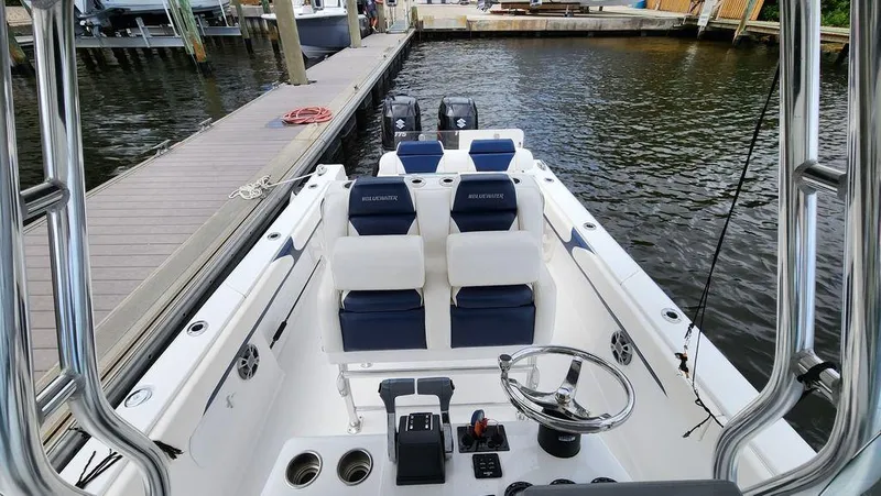 Slide: The Image of 2015 Bluewater 2550 boat interior with seating and controls, docked by the water. - 16