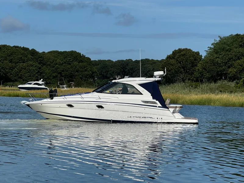 Slide: The Image of 2016 Regal 35 Sport Coupe cruising on a calm lake with lush green trees. - 2