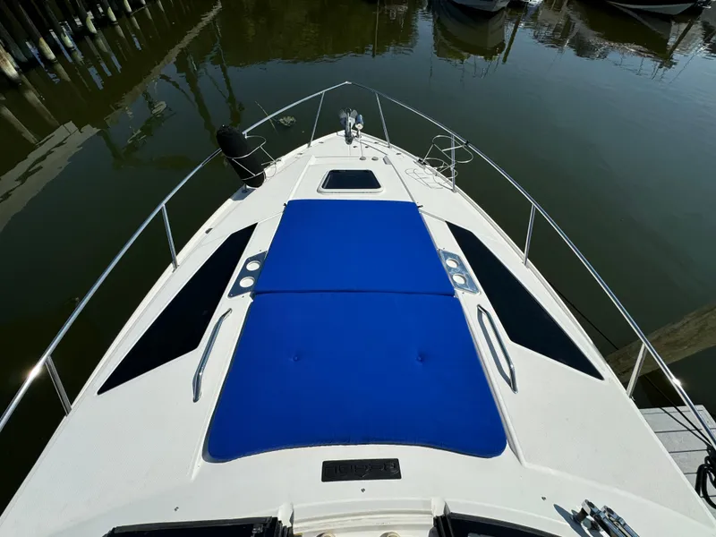 Slide: The Image of 2016 Regal 35 Sport Coupe boat with blue sunpad on deck, docked in marina. - 42
