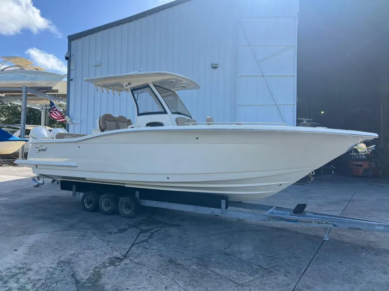 Slide: The Image of 2025 Scout 277 LXF boat on trailer outside a warehouse. - 0