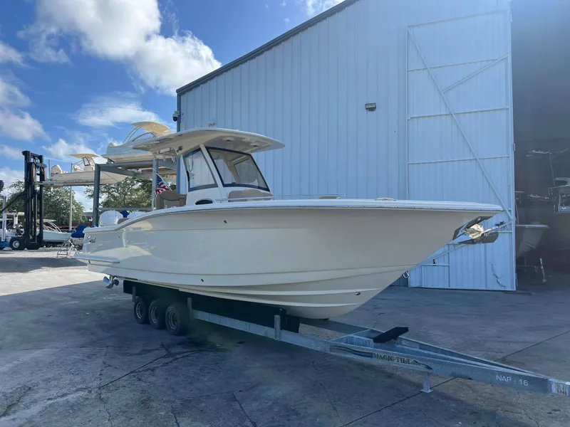 Slide: The Image of 2025 Scout 277 LXF boat on trailer outside a warehouse. - 1